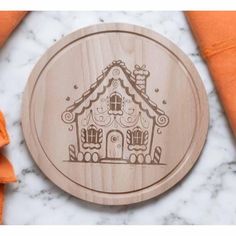 a wooden coaster with a gingerbread house on it and orange napkins next to it