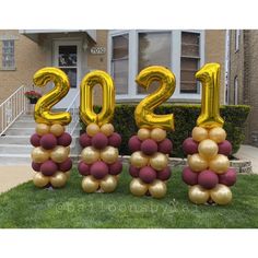 the numbers 2012 are made out of balloons in front of a house with flowers and bushes