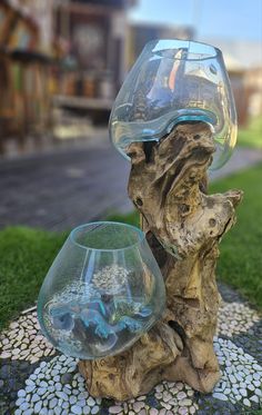 a glass vase sitting on top of a tree stump next to a bowl filled with water