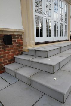 a set of concrete steps leading up to a brick building with white doors and windows