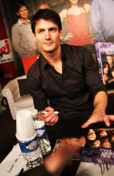 a man sitting at a table in front of posters