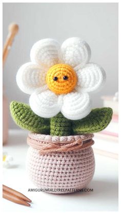 a crocheted flower sitting in a pot with leaves and flowers on the top