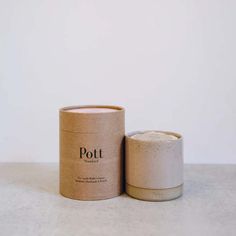 a white cup sitting on top of a table next to a brown paper container with the word pot printed on it