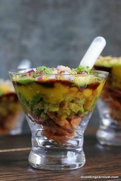 two glasses filled with food on top of a wooden table