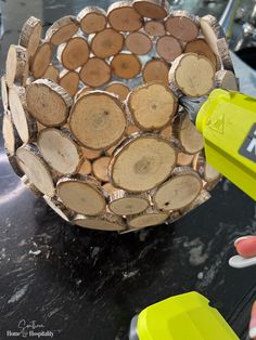 a person is holding a piece of wood in front of a basket made out of logs