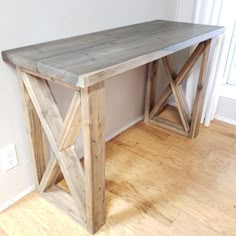 a wooden table sitting on top of a hard wood floor next to a white wall