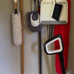 several cleaning supplies are hanging on the wall next to brooms and mop heads