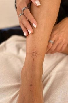 a woman with white nails and a star tattoo on her left leg, sitting on a bed