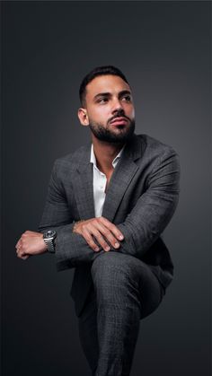 a man in a suit sitting on the ground with his arms crossed and looking off to the side