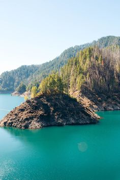 an island in the middle of a lake surrounded by trees