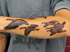 a man with a tattoo on his arm that has ducks flying in the air