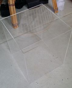 a clear table sitting on top of a floor next to a black couch and chair