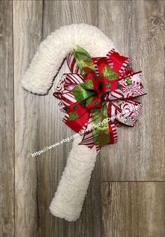 a white and red christmas wreath on top of a wooden floor with candy canes