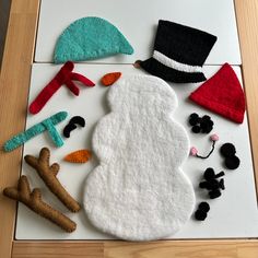 a snowman made out of felt on top of a wooden table next to other items