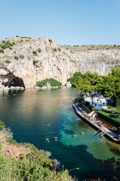 people are swimming in the water near some cliffs