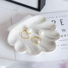 a pair of gold rings sitting on top of a white flower shaped object next to a magazine