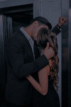 a man in a suit and tie hugging a woman's head with her eyes closed