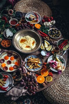 an assortment of food is arranged on a table with plates and utensils around it