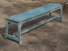 a blue bench sitting on top of a dirt field