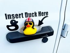 a rubber duck sitting on top of a car door handle with an inset duck here sign above it