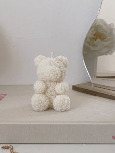 a white teddy bear sitting on top of a table next to a mirror and chain