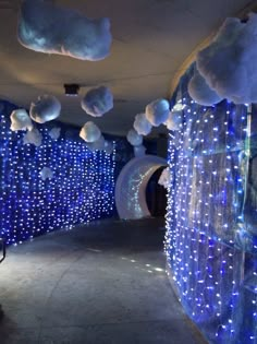 a hallway with blue lights and clouds hanging from the ceiling, along with white fluffy balls