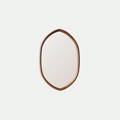 an oval wooden mirror hanging on the wall