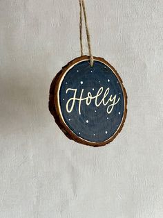 a wooden ornament with the word holly hanging from a rope on a wall