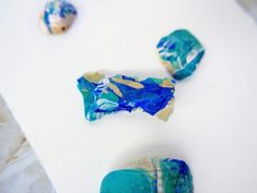 three pieces of blue and gold marble on a white surface with other rocks in the background