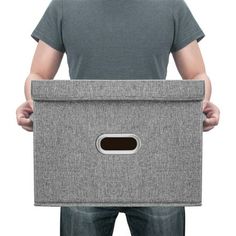 a man is holding a brown box with a hole in the middle and his hands behind him