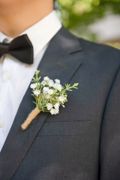 a man in a suit and bow tie with flowers on his lapel flower pin