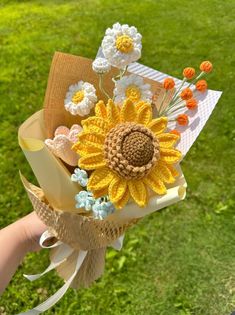 a person holding a bouquet of flowers in their hand with grass and trees in the background