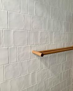 a bathroom with white brick walls and wooden handles on the wall, along with a toilet paper dispenser