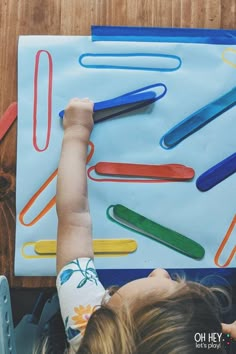 a young child is playing with colored paper clips