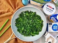 a bowl filled with spinach next to eggs and yogurt