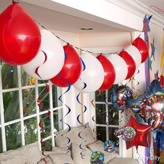 balloons, streamers and streamers are hanging from the ceiling in front of a window