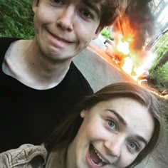 two people standing next to each other near a fire