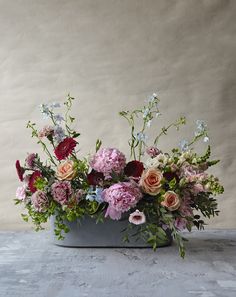 an arrangement of flowers in a gray vase on a table