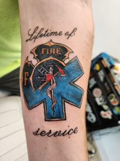 a tattoo on the arm of a person with a cross and firefighter's emblem