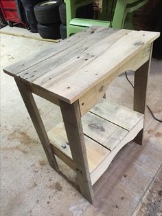 a wooden table sitting on top of a floor next to a pile of tires in a garage