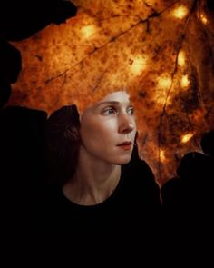 a woman with an umbrella over her head and lights on the leaves above her head