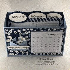 a desk calendar is shown in a blue and white card holder with flowers on it