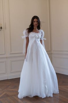 a woman in a white dress standing on a wooden floor