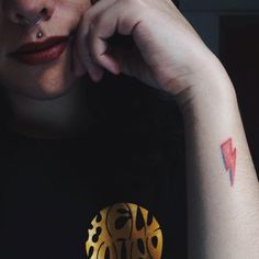 a close up of a person with a tattoo on their left arm and her right hand near her face