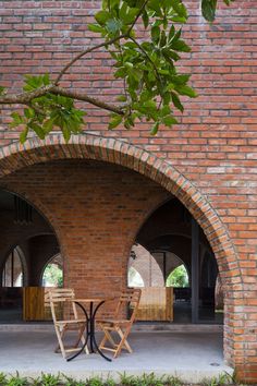 two wooden chairs sitting under an arched brick wall