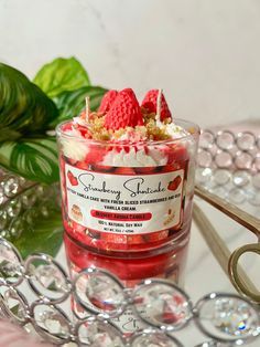 a strawberry shortcake in a small glass bowl on a tray next to a green plant