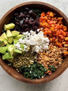 a wooden bowl filled with different types of food on top of a white countertop