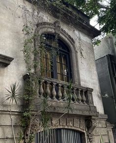 an old building with plants growing on the balcony