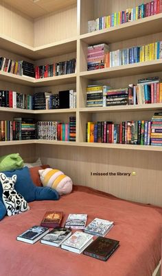 there is a bed with books on it and many other books in the shelves behind it