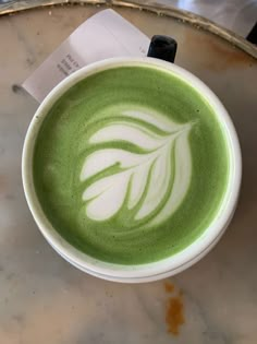 a cup of green tea with white designs on it sitting on top of a table